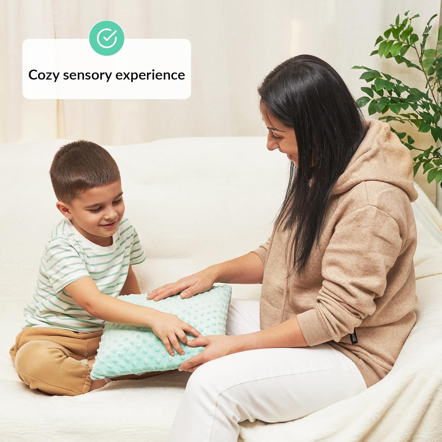 Woman and child sitting on a couch with a sensory pillow, labeled 'Cozy sensory experience'.